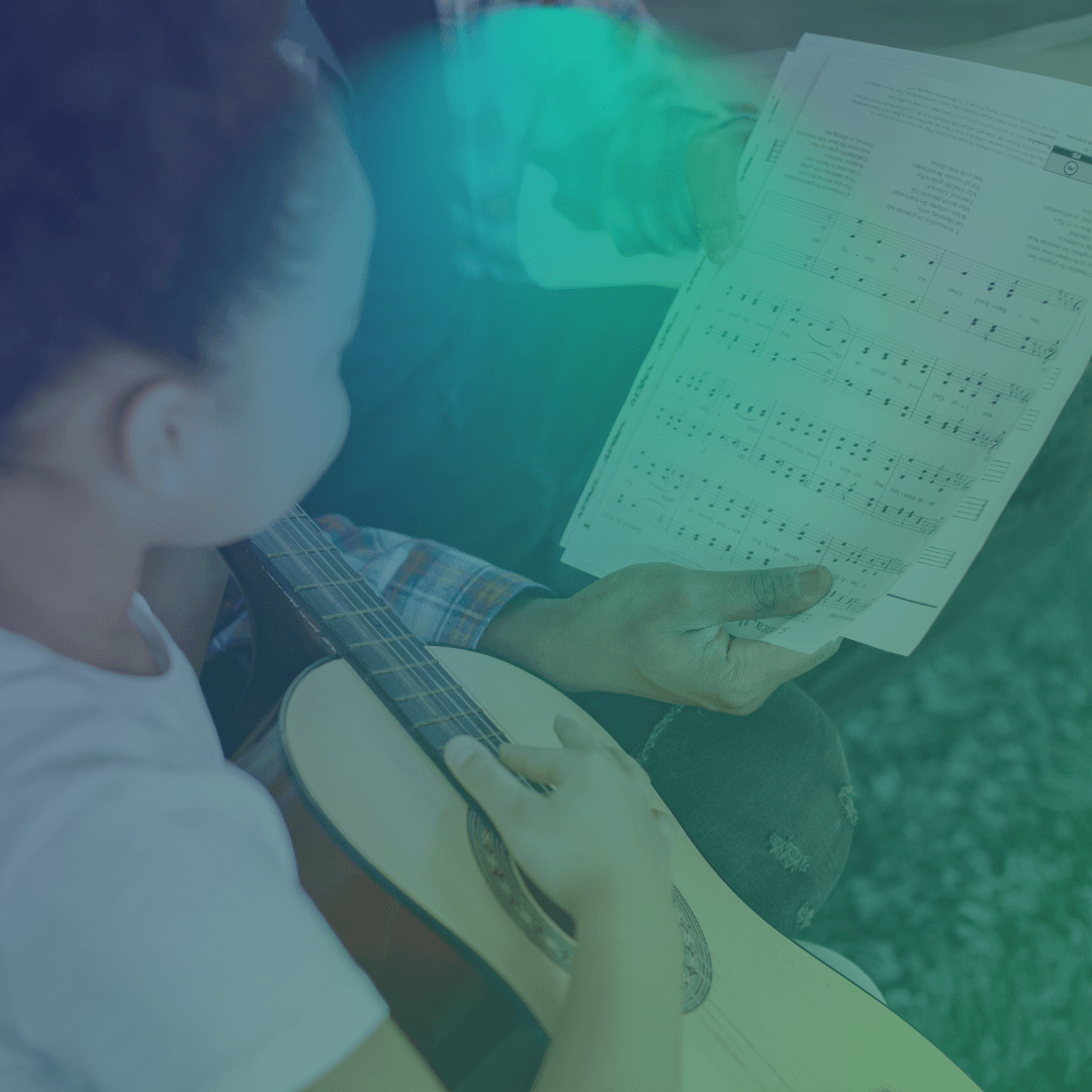 Aluno tocando violão lendo partitura
